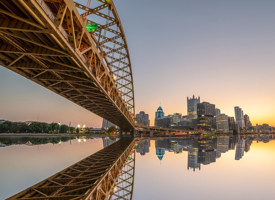 About Our Agency - Aerial View of a Bridge Reflecting in the River Below During Sunset